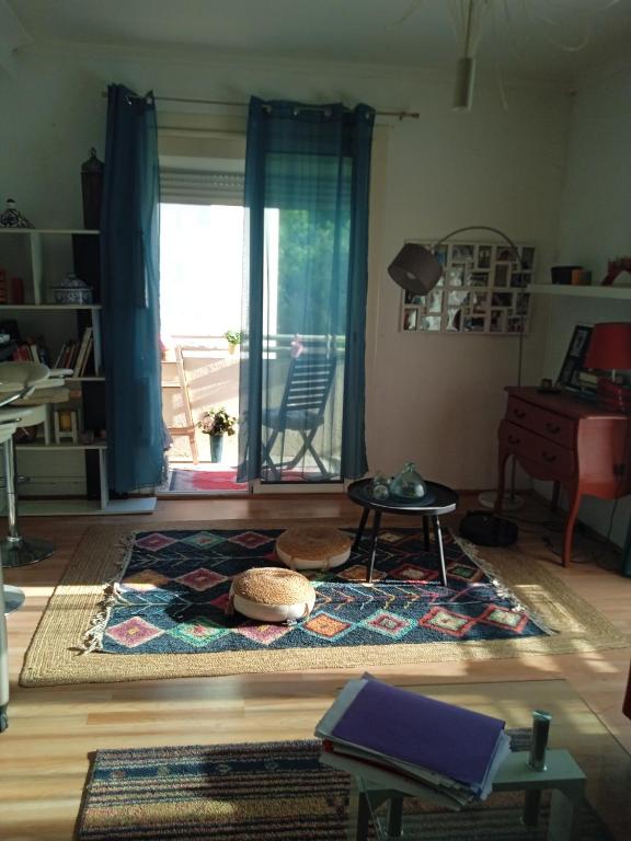 a living room with a rug and a large window at Chambre cosy chez Schéhérazade in Toulon