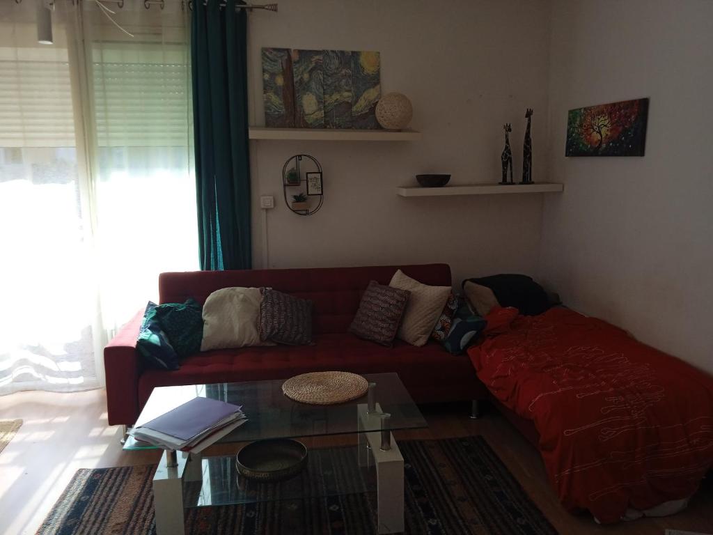 a living room with a red couch and a glass table at Chambre cosy chez Schéhérazade in Toulon