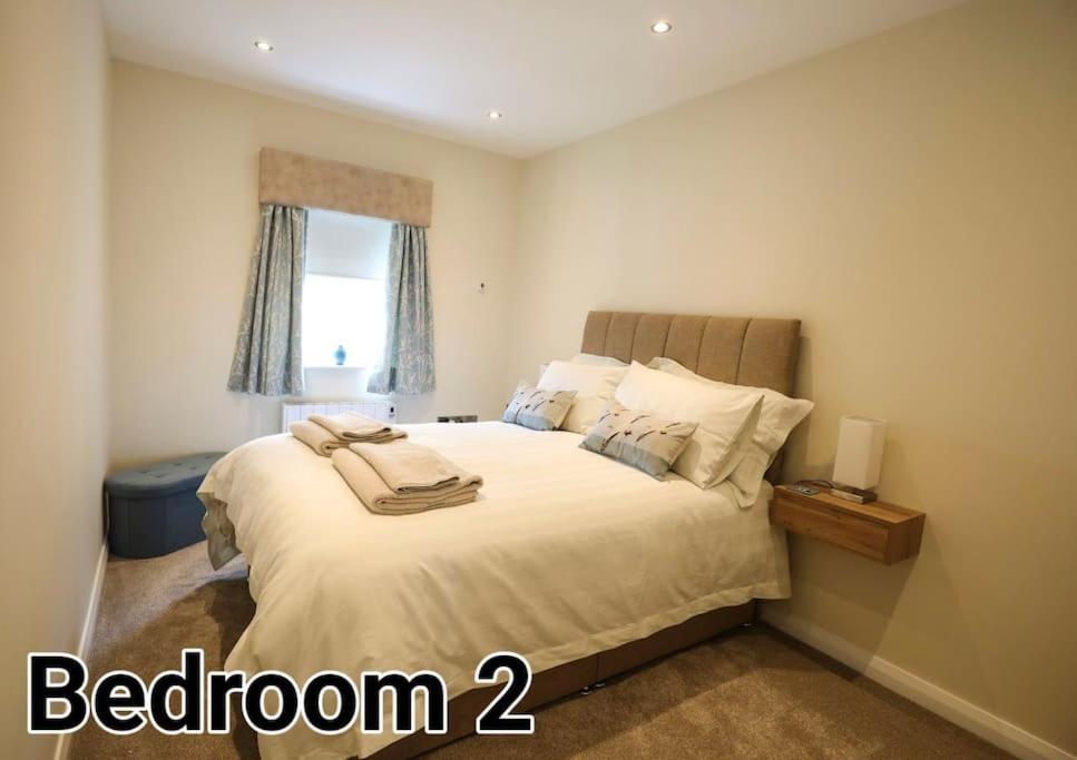 a bedroom with a white bed with a window at Seafront Sanctuary Ballycastle in Ballycastle