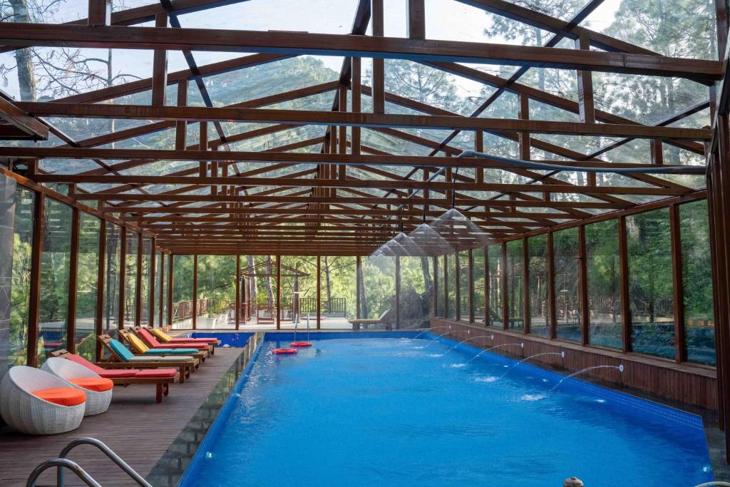an indoor pool with chairs and a swimming pool at Chillaru Spa & Resort in Kasauli