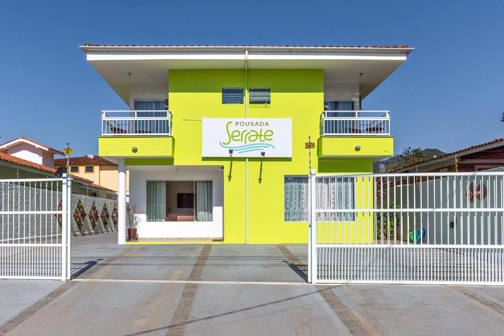 un edificio amarillo con un cartel. en Pousada Serrate, en Ubatuba