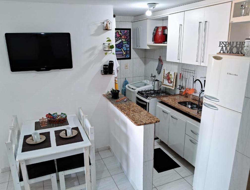 cocina con armarios blancos y TV en la pared en Solar do Pontal - Lindo Apartamento a 600m da praia, en Río de Janeiro