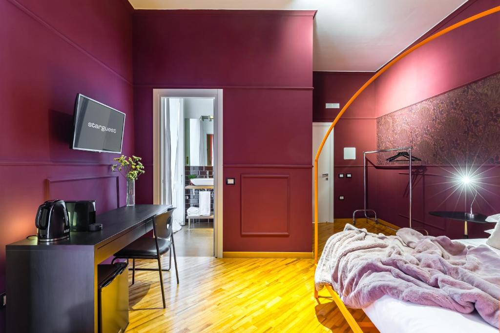 - une chambre avec des murs violets, un lit et un bureau dans l'établissement Starguest Dante, à Naples