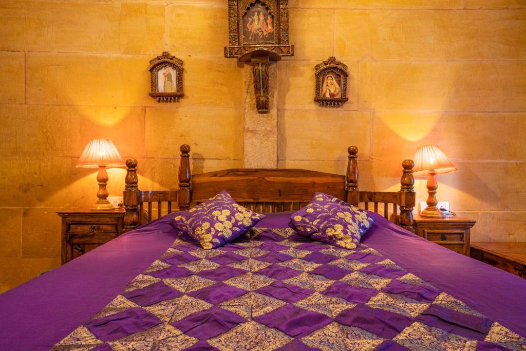 a bedroom with a purple bed with two lamps at Hotel Garh Jaisal Haveli in Jaisalmer