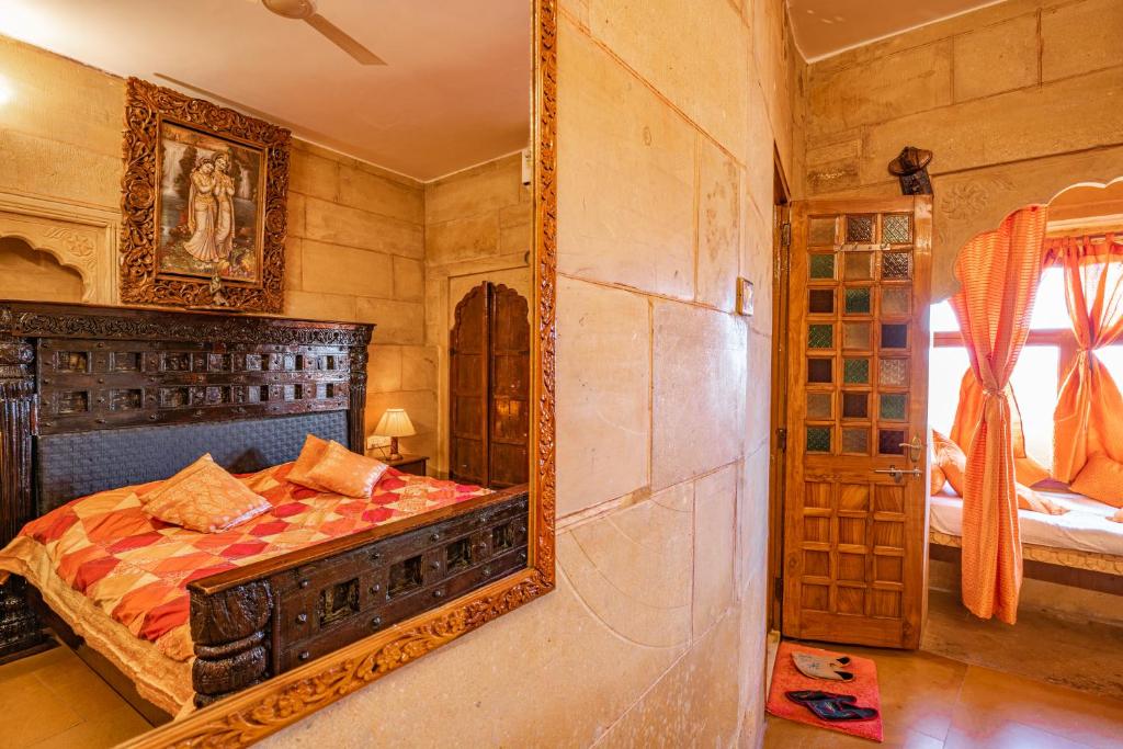 a bedroom with a bed with a mirror on the wall at Hotel Garh Jaisal Haveli in Jaisalmer