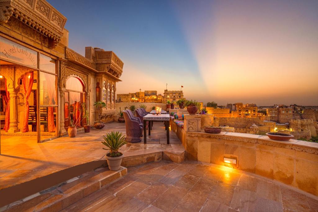 eine Terrasse mit Blick auf die Stadt bei Sonnenuntergang in der Unterkunft Hotel Garh Jaisal Haveli in Jaisalmer