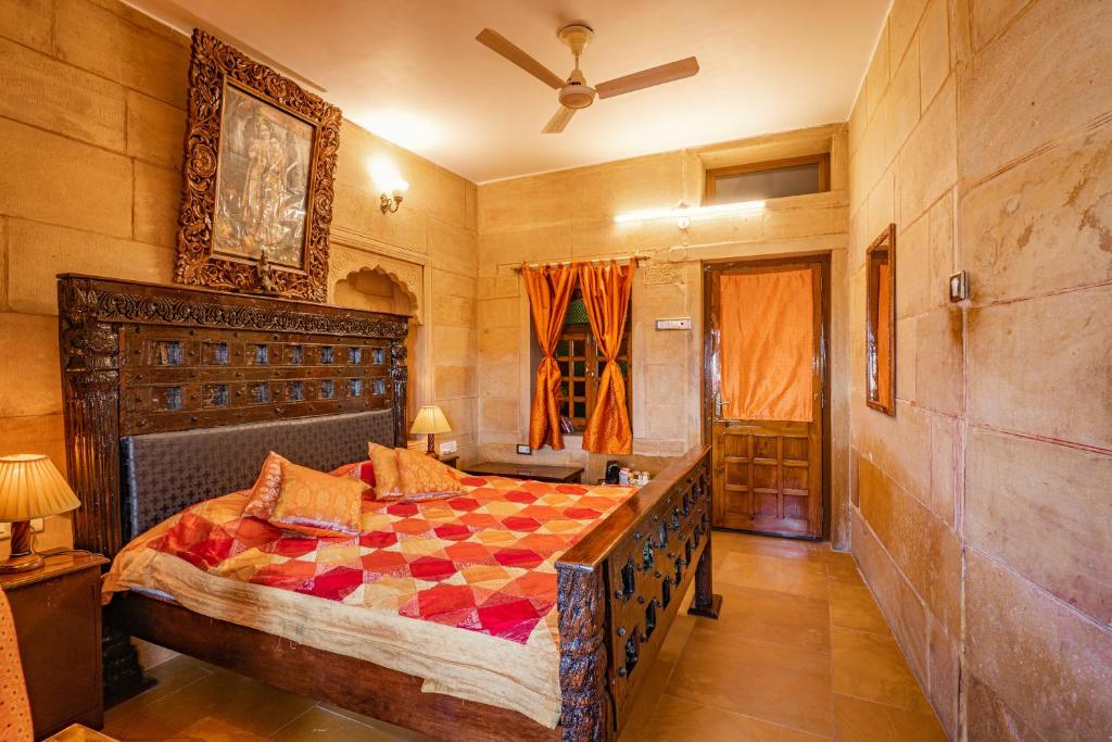 a bedroom with a bed and a ceiling fan at Hotel Garh Jaisal Haveli in Jaisalmer