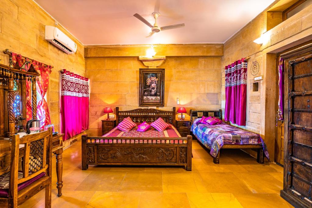 a bedroom with two beds and red curtains at Hotel Garh Jaisal Haveli in Jaisalmer