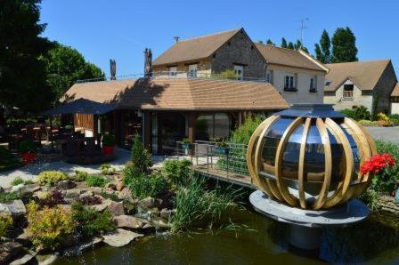 une maison avec un grand bol au milieu d'un jardin dans l'établissement Domaine de la Haie des Granges, à Ménilles
