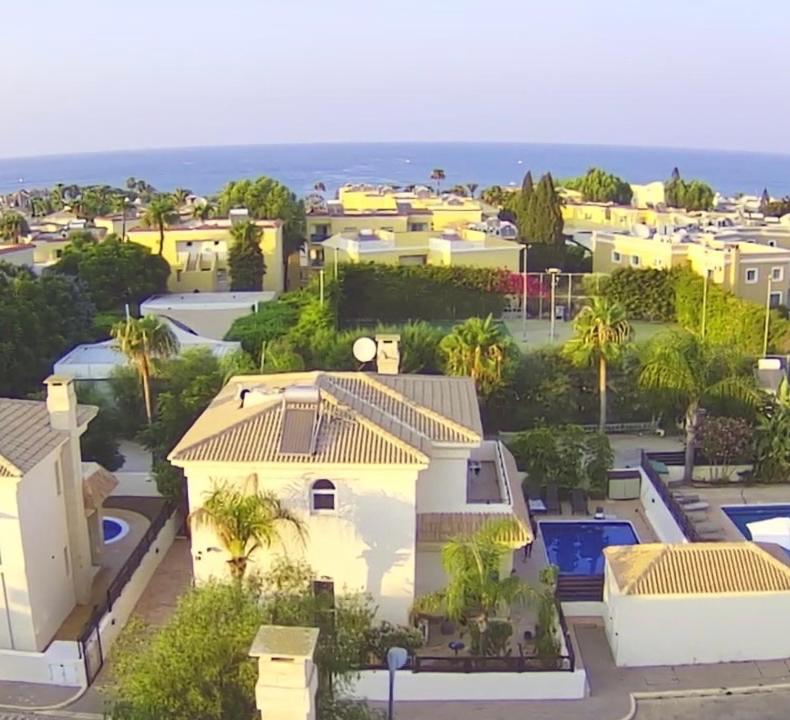 Vista árida de una casa con palmeras y el océano en Luxury spacious holiday Villa with heated swimming pool, en Paralimni