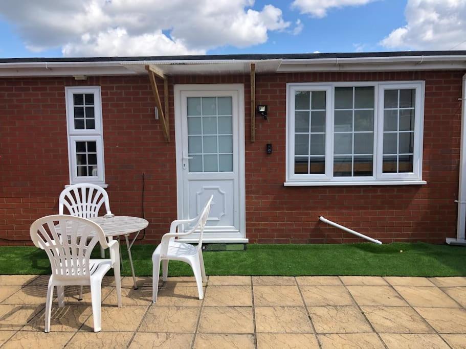 two chairs and a table in front of a brick house at Private entrance studio , garden and free parking in Slough
