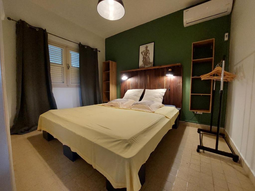 a bedroom with a large bed with a green wall at KAZLETANG in Le Poteau