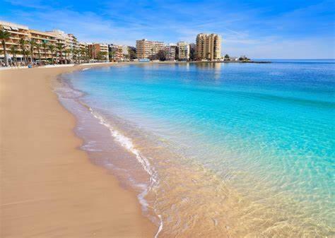 a beach with buildings in the background and the ocean at Policarpo-centro in Torrevieja