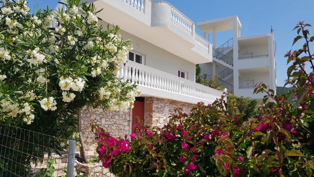 una casa blanca con una puerta roja y flores en Sunny Villa, en Ksamil