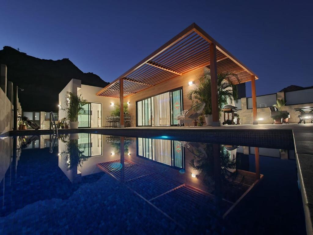 a house with a swimming pool at night at Villa de lujo con piscina climatizada in Mogán