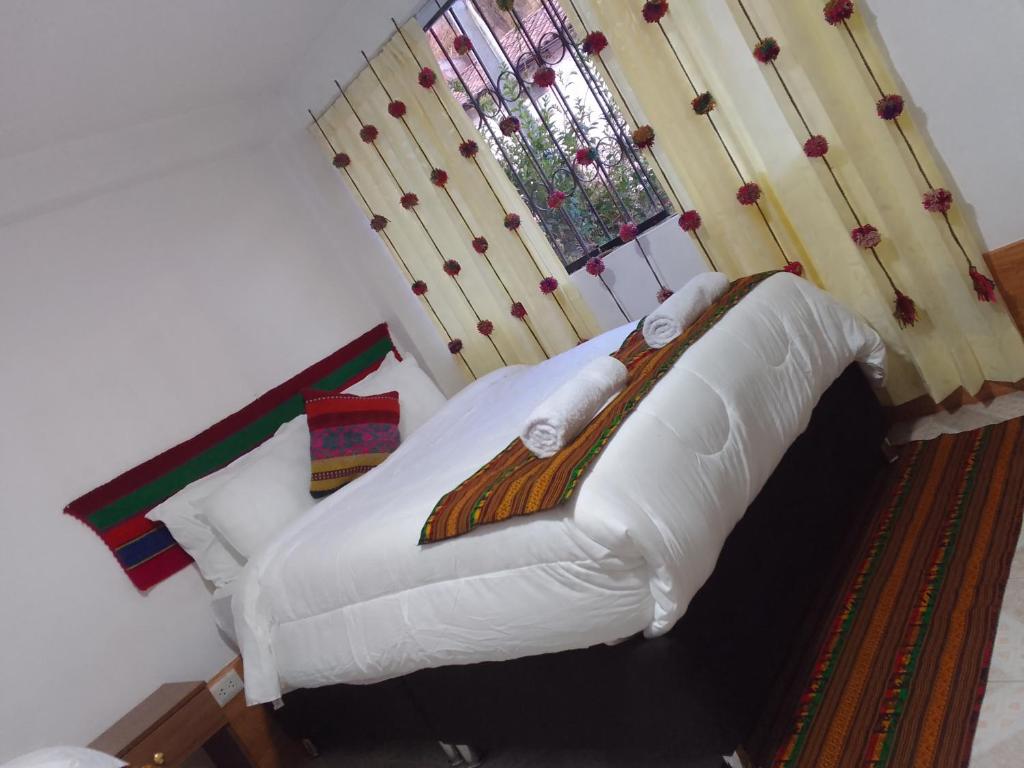 1 dormitorio con 1 cama con sábanas blancas y ventana en Incas Town Inn, en Cusco