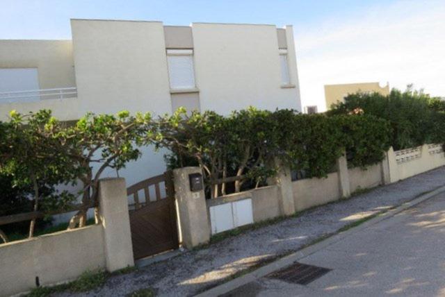 une clôture devant un bâtiment à côté d'une rue dans l'établissement Agréable Maison Familiale 100 m de la plage 6AVAN5, au Barcarès