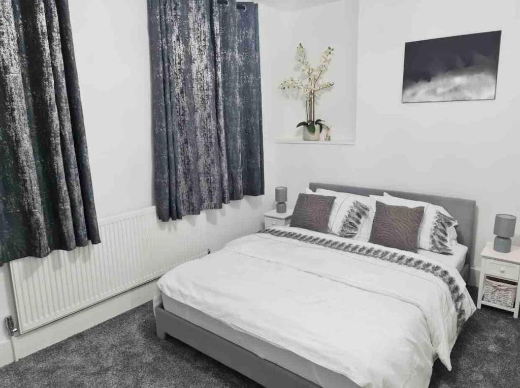 a white bedroom with a bed and two windows at L A PLACE Croydon, London in Norwood