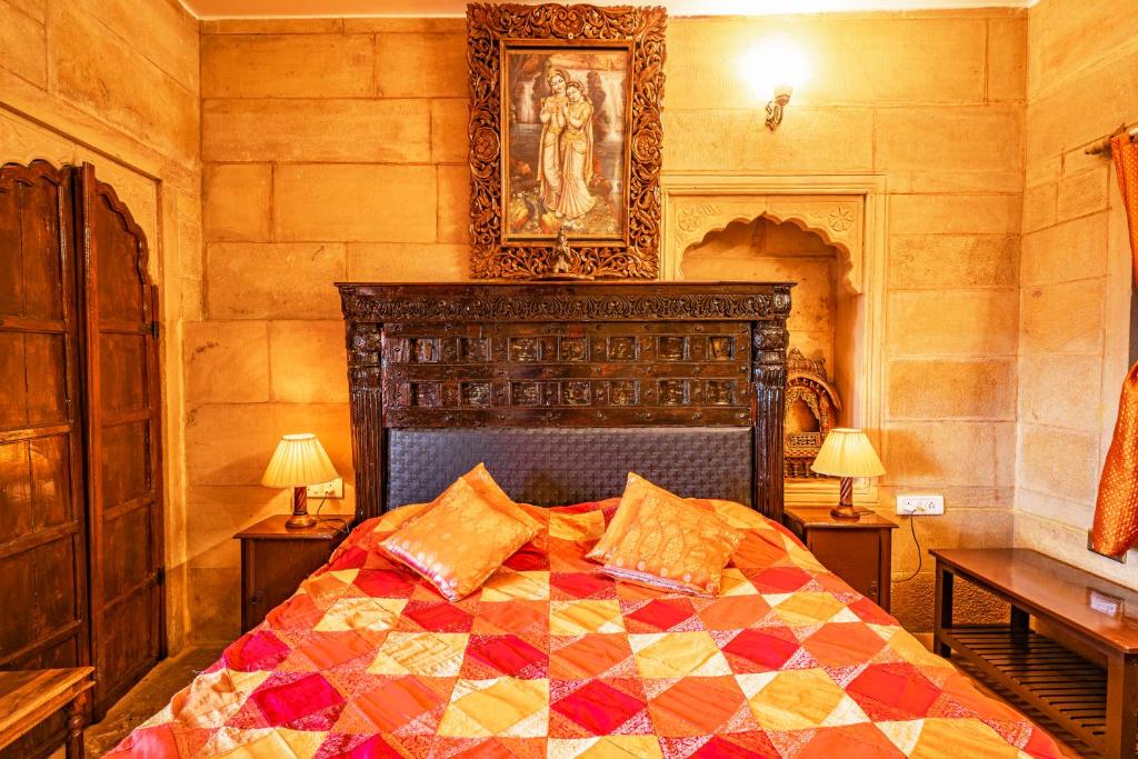 a bedroom with a bed with a quilt on it at Hotel Garh Jaisal Haveli in Jaisalmer