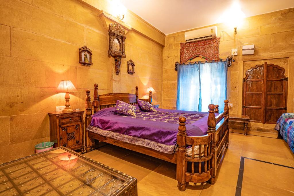 a bedroom with a wooden bed with purple sheets at Hotel Garh Jaisal Haveli in Jaisalmer