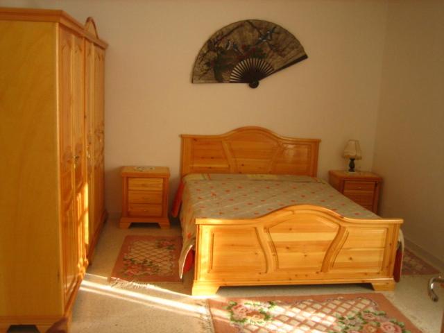 - une chambre avec un lit en bois et 2 tables de chevet dans l'établissement Ahlem palmeraies résidence, à La Marsa