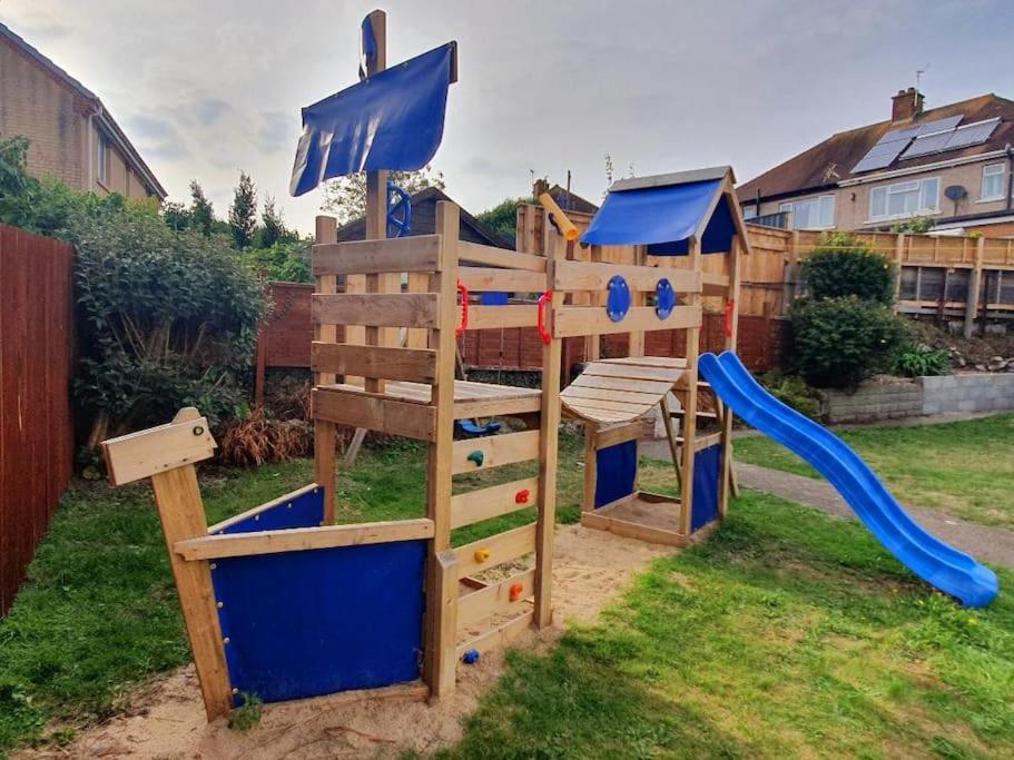 a wooden playground with a slide in a yard at Fabulous family house next to the beach in Nottage