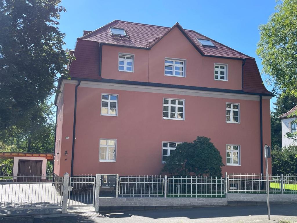 una casa rossa con una recinzione di fronte di Apartment-Haus Landeskrone a Dresda