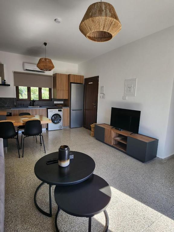 a living room with a table and a kitchen at Adamandri Lodge - Prime Location in Ayia Napa