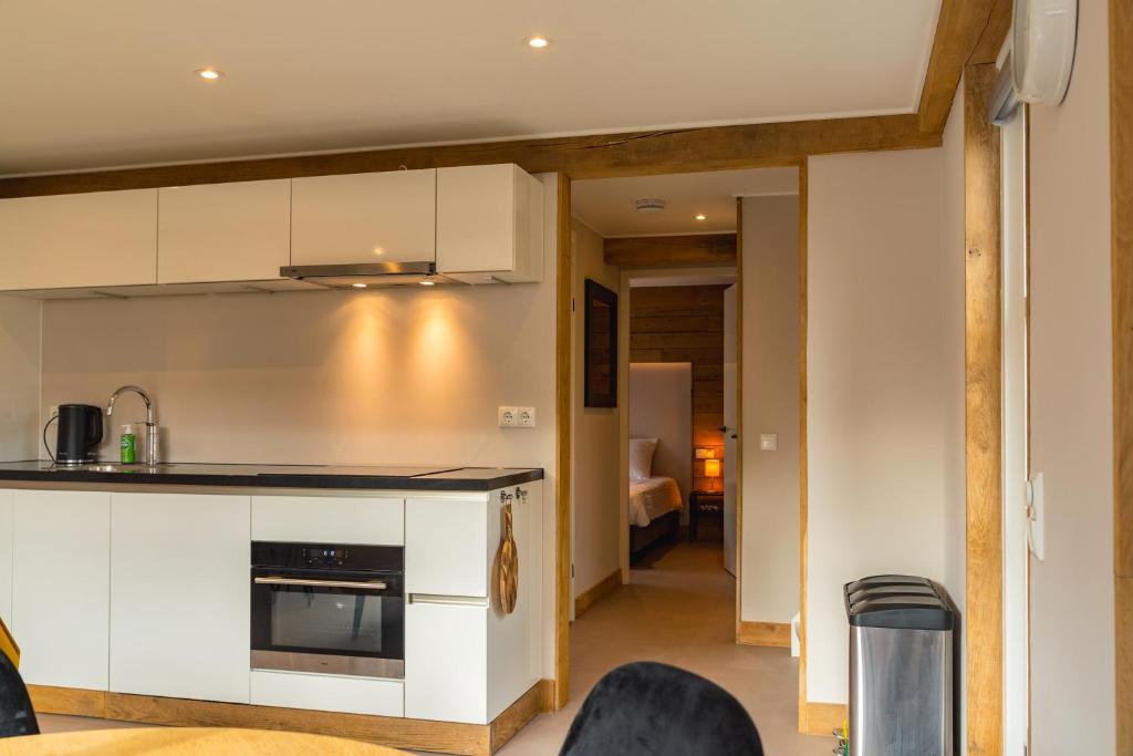 uma cozinha com armários brancos e uma sala de estar em Sallands huisje em Haarle