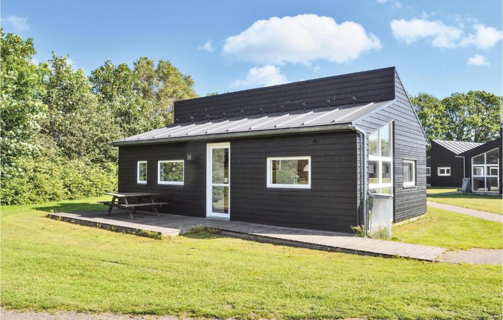 ein schwarzes winziges Haus mit einem Picknicktisch im Hof in der Unterkunft Pet Friendly Home In Spjald With Kitchen in Spjald
