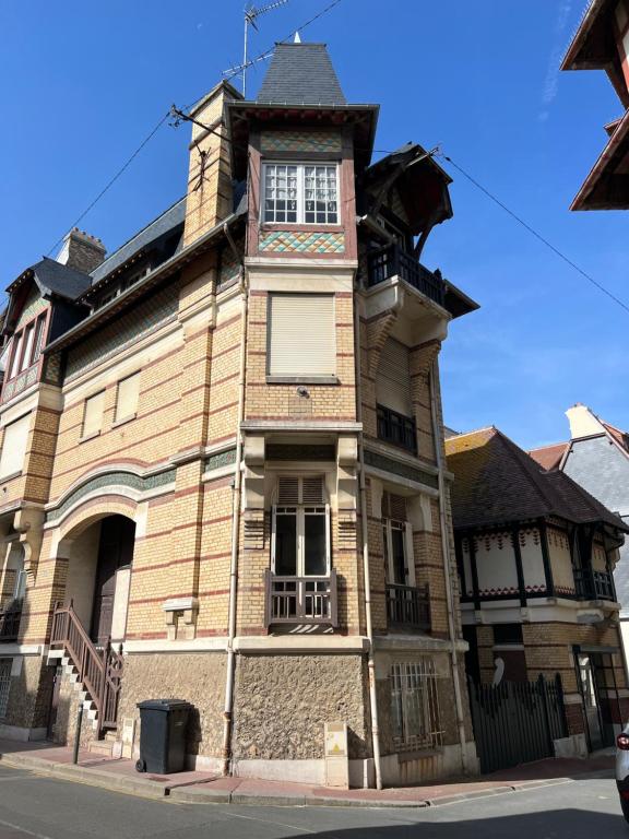 um edifício antigo com uma torre de relógio numa rua em Les Grands Ducs em Trouville-sur-Mer