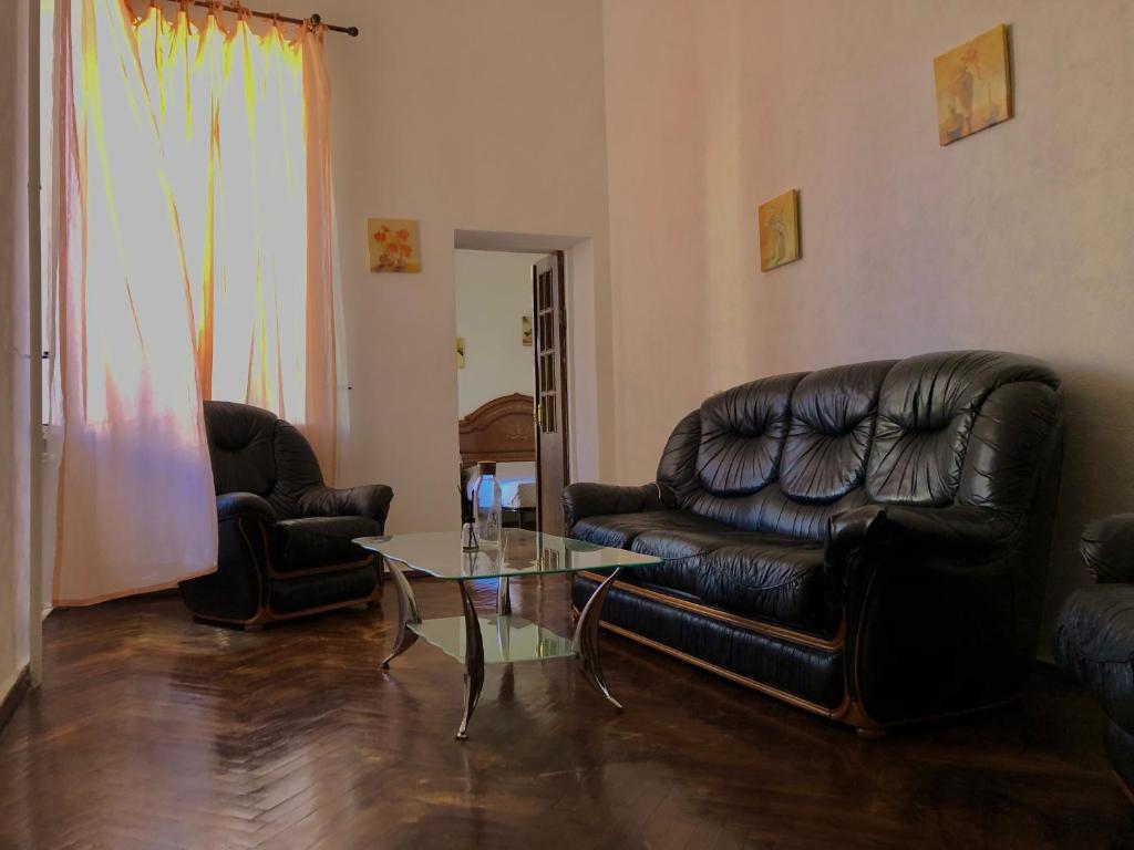 sala de estar con muebles de cuero negro y mesa de cristal en Comfortable apartments near Gulliver, en Kiev