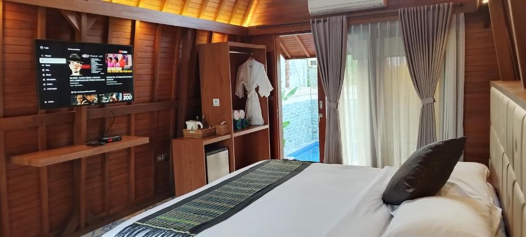 a bedroom with a bed and a flat screen tv at Kori Maharani Villas & Resort in Keramas