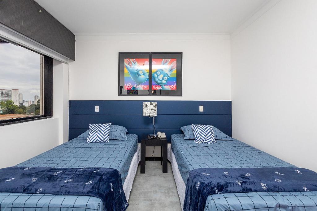 2 camas en una habitación con paredes azules y blancas en LFlats no Hotel Aeroporto Congonhas en São Paulo