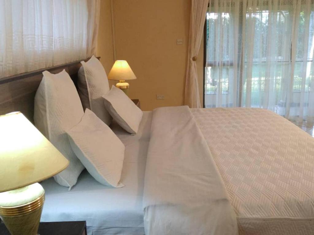 a bedroom with a bed with white sheets and pillows at Charming 6-Bed House with Swimming Pool in Harare in Harare