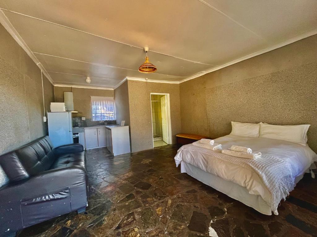 een slaapkamer met een bed en een bank erin bij Lindy's Guesthouse in Maseru