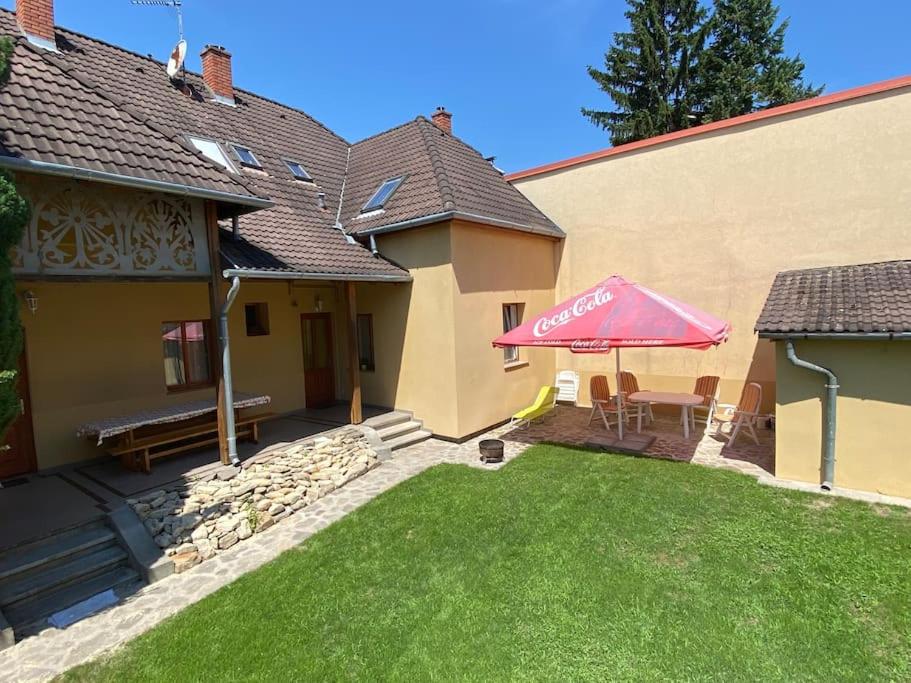 a house with a lawn with a table and an umbrella at Körtefa Vendégház Keszthely in Keszthely
