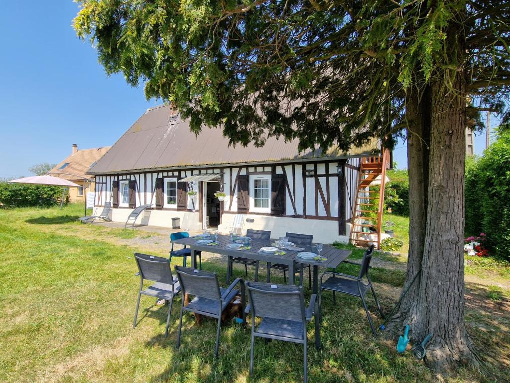 a table and chairs under a tree in front of a house at maison normande en paix 