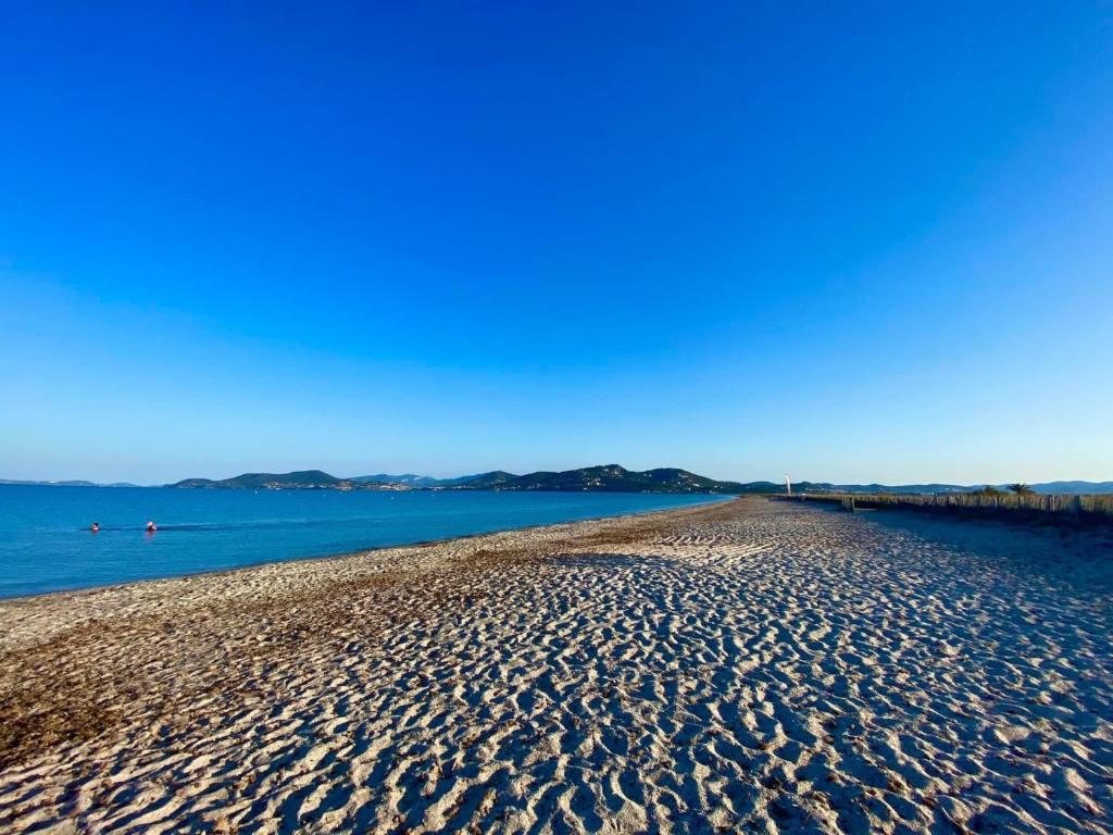 a sandy beach next to a body of water at LA BADINE 5p Plage piscine clim jacuzzi parc luxuriant in Hyères