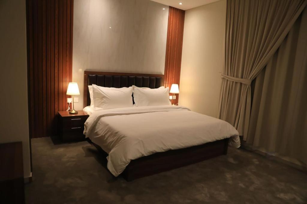 بريفير للأجنحة الفندقية Privere Hotel Suites في الرياض: غرفة نوم بسرير كبير ومصباحين