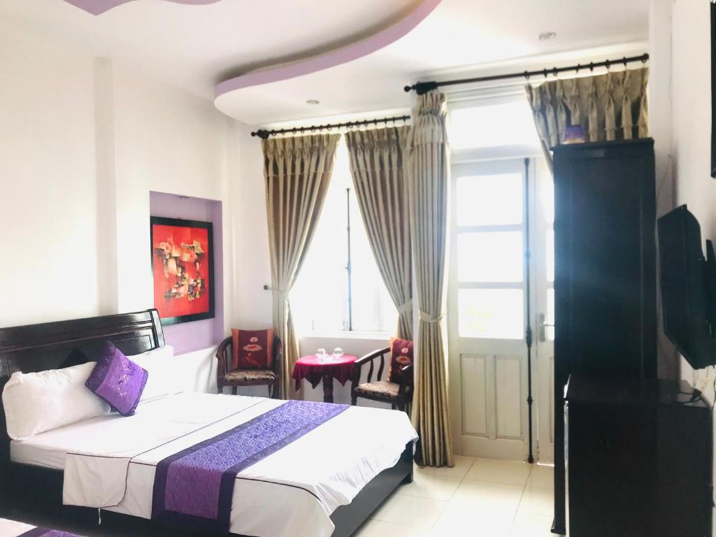 a bedroom with a bed and a table and a window at Huế thương Hotel in Hue