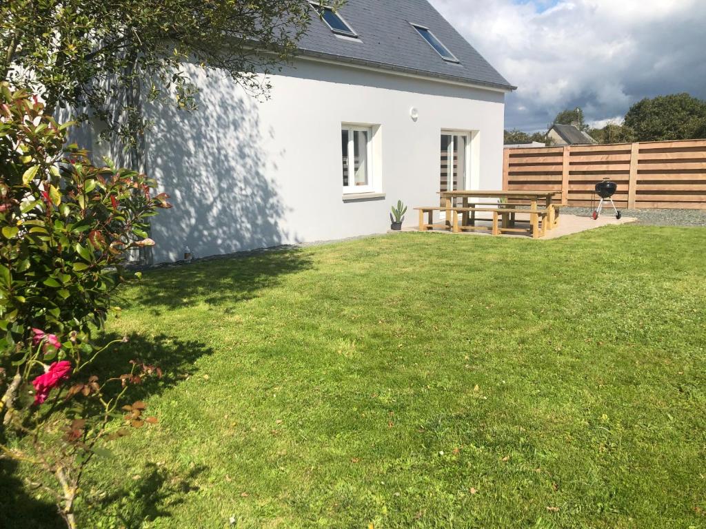 une cour avec une maison blanche et un banc en bois dans l'établissement Maison familiale à 1km de la mer, à Blainville-sur-Mer