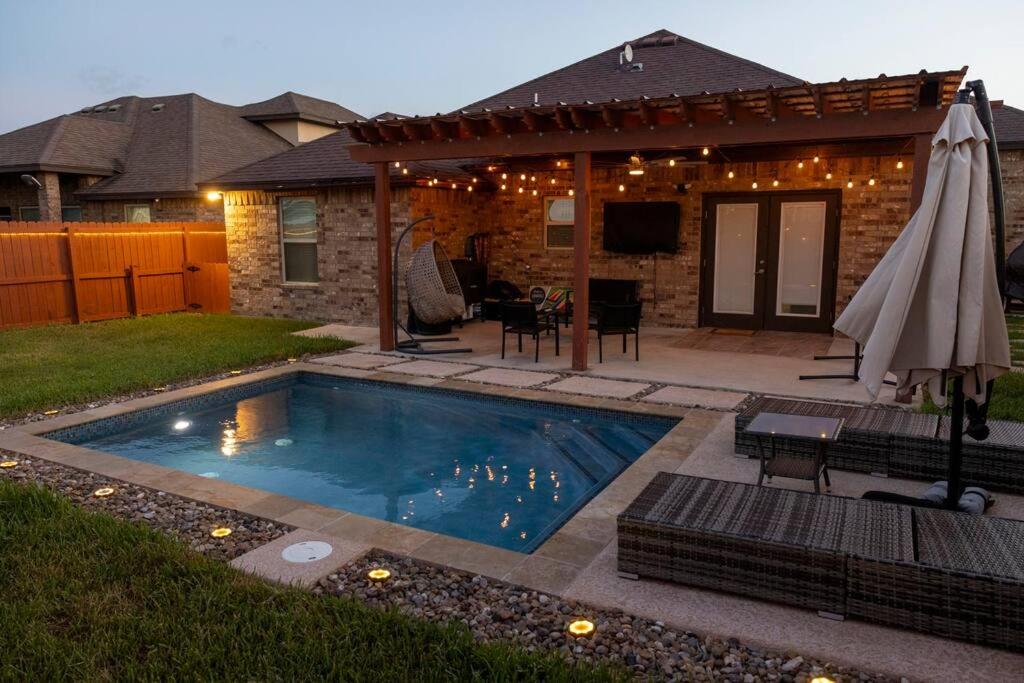 a swimming pool in a backyard with an umbrella at Cozy home with POOL and free WIFI in Brownsville