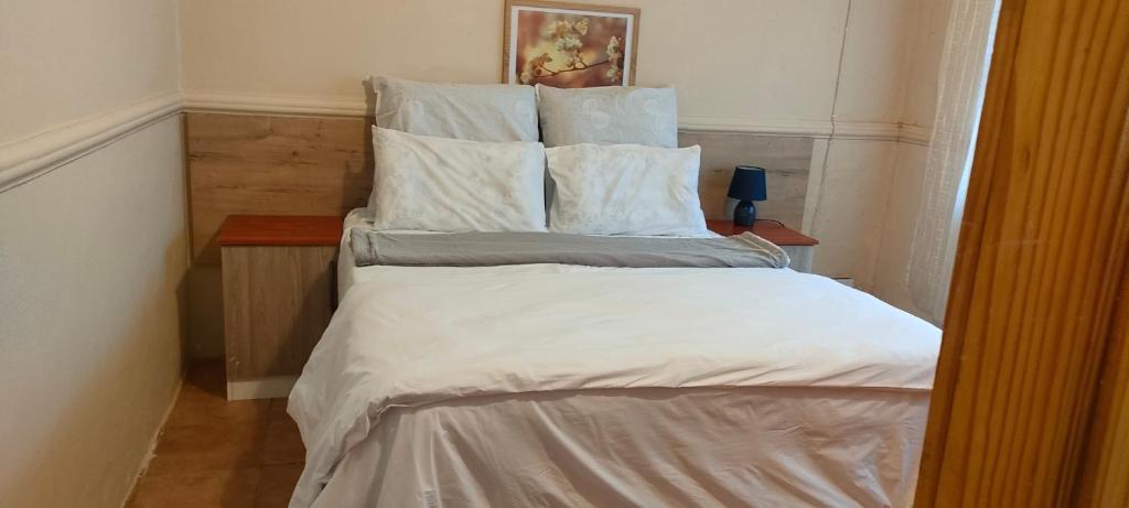 uma cama grande com lençóis brancos e almofadas em Mabel's house em Sabie