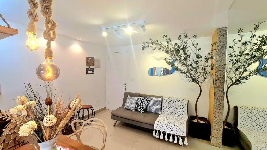 ein Wohnzimmer mit einem Sofa und einem Baum an der Wand in der Unterkunft Apto Aconchegante em Búzios - Condomínio Talhamar in Búzios