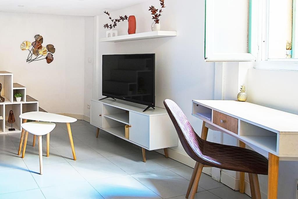 uma sala de estar com uma televisão, uma secretária e cadeiras em Cosy studio - Best location em Nice