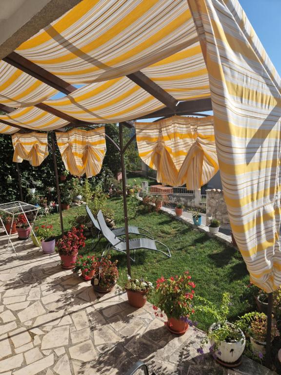 un parasol jaune et blanc sur une terrasse avec des plantes en pot dans l'établissement Rooms Marijeta, à Skradin