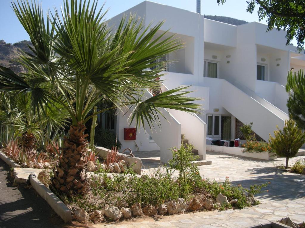 a building with a palm tree in front of it at Mandorla Apartments in Lardos