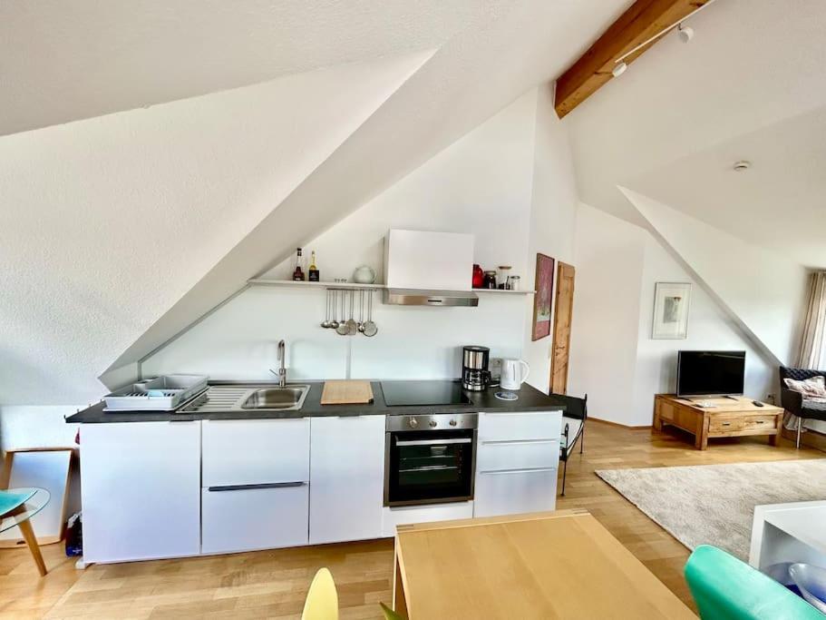 a kitchen with white cabinets and a living room at Sonnige Wohnung am Lindenberg in Lohfelden