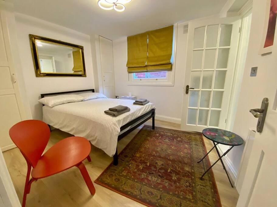 1 dormitorio con cama, silla y espejo en Cosy Studio in trendy Islington, w/private garden!, en Londres